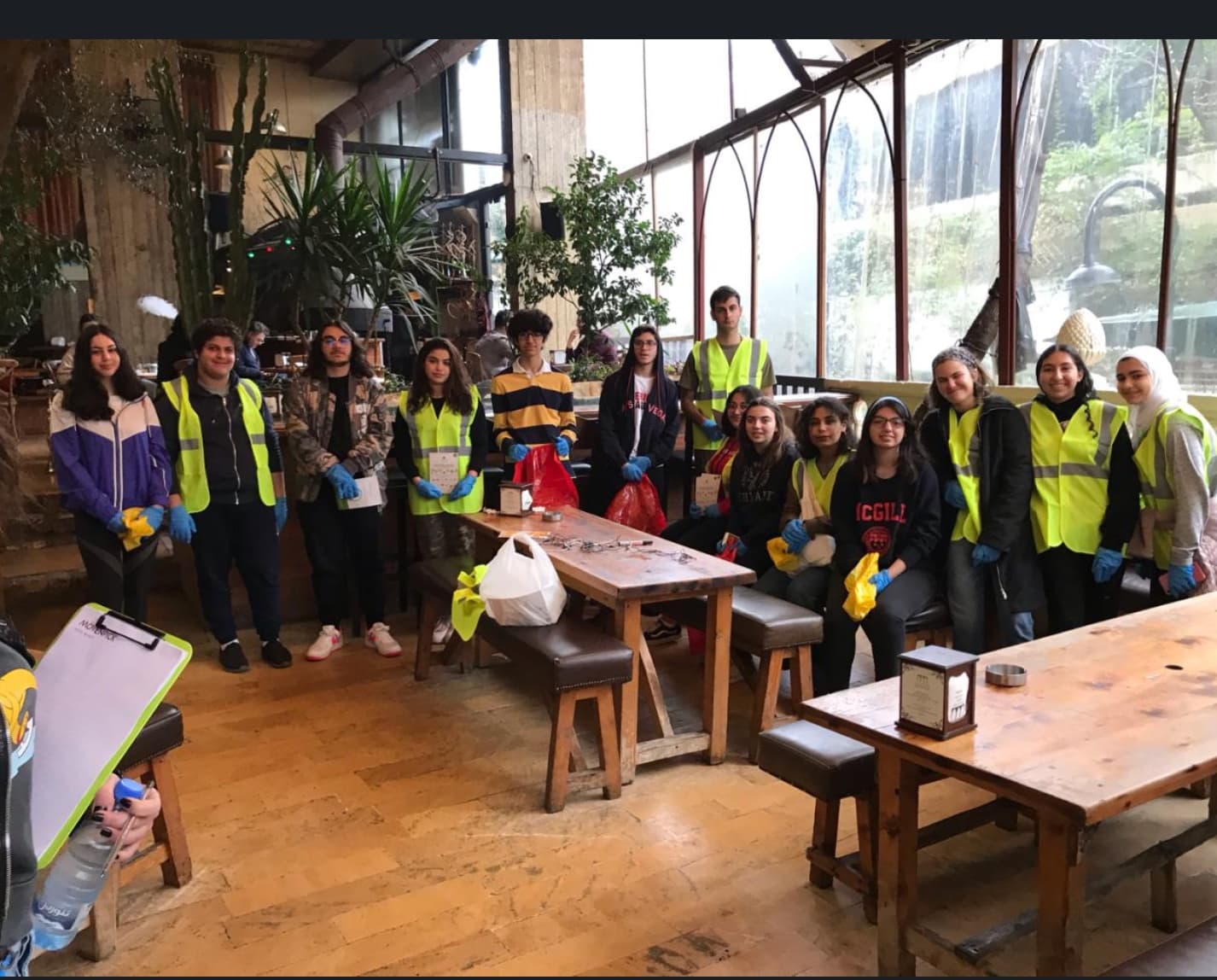 Student volunteers in vests holding collection bags inside a restaurant